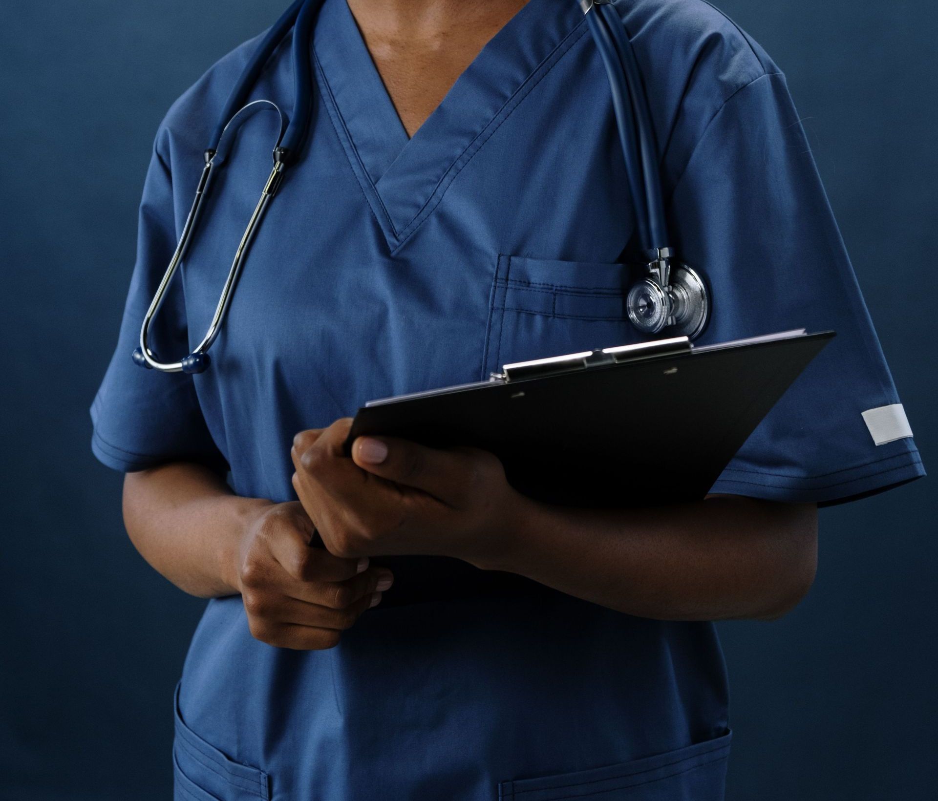 Professional nurse in blue scrubs holding a clipboard, conveying confidence and care.