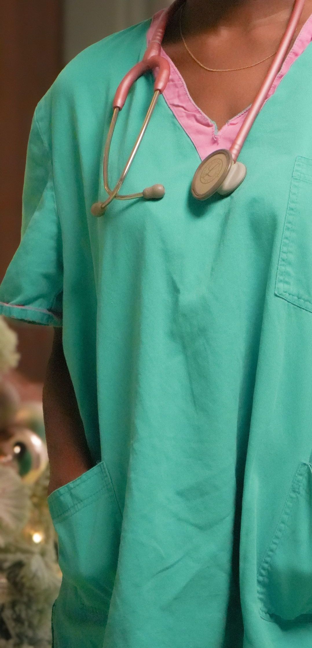Confident female nurse smiling with stethoscope in hospital corridor. Medical professional in scrubs.